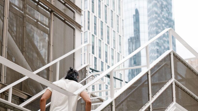 Person steigt eine Aussentreppe zwischen Hochhaeusern hinauf