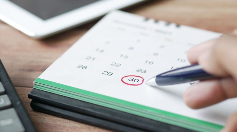 Hand, die mit einem Stift einen Termin im Kalender ankreuzt